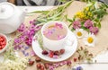 Herbal tea with rosehip, chamomile and clover in a white cup on a wooden table with flowers Royalty Free Stock Photo