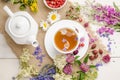 Herbal tea with rosehip, chamomile and meadowsweet in a white cup on a white wooden table with flowers Royalty Free Stock Photo