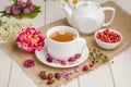 Herbal tea with rosehip and meadowsweet in a white cup on a white wooden table with flowers Royalty Free Stock Photo
