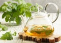 Herbal tea in a transparent teapot on the table and sprigs of fresh Melissa lemon balm and mint
