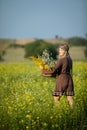 A young herbalist walks through a field of rapeseed with a basket of harvested herbs. Goldenrod and wintercress.