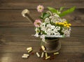 Herbs and a thermometer in a copper mortar and pestle, capsules and pills scattered around Royalty Free Stock Photo