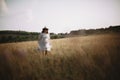 Herbs and wildflowers in sunny meadow in mountains and blurred image of girl in linen dress walking. Boho woman relaxing in Royalty Free Stock Photo