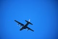 HERCULES C-130 WITH LANDING GEAR DOWN FLYING LOW AGAINST BLUE SKY