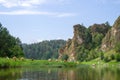 Herd of cows in meadow near river with beautiful rocks. Cute summer rural landscape Royalty Free Stock Photo