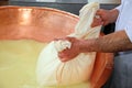 Herdsman Cheesemaker collects cheese from the copper cauldron w Royalty Free Stock Photo