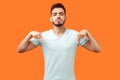 Here and right now. Portrait of bossy strict brunette man pointing down and looking arrogant. isolated on orange background