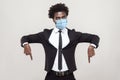 Here and right now. Portrait of serious young handsome worker man in black suit with surgical medical mask standing, looking and Royalty Free Stock Photo