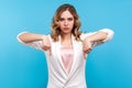 Here and right now! Portrait of strict serious woman boss pointing down with angry face. isolated on blue background