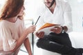 Here`s pencil for corrections. Redhead girl and bearded man sitting on the sofa and having conversation about their