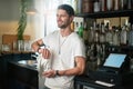 Here to cater to your beverage needs. a happy young waiter polishing a glass behind the bar.