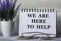 WE ARE HERE TO HELP - words in a notebook on a light background with glasses and a bouquet of lavender Royalty Free Stock Photo