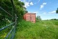 Herefordshire / UK - 6 June 2021: Mud coloured brown shipping container in Herefordshire field next to metal gate