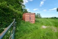 Herefordshire / UK - 6 June 2021: Mud coloured brown shipping container in Herefordshire field next to metal gate