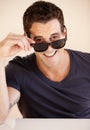 Heres looking at you. Portrait of a handsome young man looking at you over his shades. Royalty Free Stock Photo