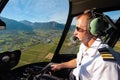 Caucasian male helicopter pilot flying a R44 type chopper over rural area