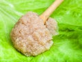 Herring caviar in wood spoon on green lettuce