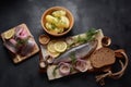 Herring fish  on wooden board  with pepper, herbs, red onion and lemon on black  background Royalty Free Stock Photo