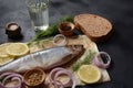 Herring fish  on wooden board  with pepper, herbs, red onion and lemon on black  background. Royalty Free Stock Photo