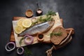 Herring fish  on wooden board  with pepper, herbs, red onion and lemon on black  background. Royalty Free Stock Photo