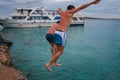 09.20.2008, Hersonissos, Crete, Greece. A young men jumping into water on background of the ship.