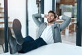 Hes bossed it today. a handsome young businessman relaxing with his feet up on a desk in a modern office. Royalty Free Stock Photo