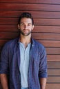 Hes an easy going guy. Portrait of a handsome man standing against a wooden wall. Royalty Free Stock Photo