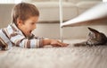 Hes even littler than me. A little boy lying on his bedroom floor and playing with a kitten. Royalty Free Stock Photo