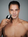 Hes an expert at grooming. Portrait of a handsome mature man shaving his face with an electric razor. Royalty Free Stock Photo
