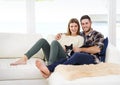 Hes a first fur baby. Portrait of a smiling young couple sitting with their cat on a sofa at home. Royalty Free Stock Photo