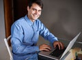 Hes a go-getter. Portrait of a confident young businessman sitting with a laptop at his desk.