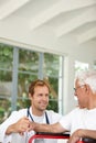 Hes really good with his senior patients. a handsome male doctor talking to his senior patient whos in a wheelchair. Royalty Free Stock Photo
