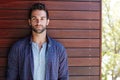 Hes got a heartbreakers smile. Portrait of a handsome man standing against a wooden wall. Royalty Free Stock Photo