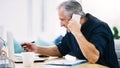 Hes having a busy day at the office today. a mature businessman writing a few notes down while answering a phone call in Royalty Free Stock Photo