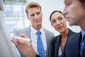 Hes an ingenious business strategist. A businessman drawing a diagram on a flip-chart as his colleagues stand by.