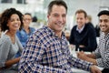 Hes the kind of team leader one can trust. Businessman smiling towards the camera with his smiling colleagues in the Royalty Free Stock Photo