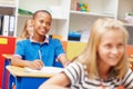 Hes making the most of his education. Young african-american student smiling at his desk in class amongst classmates - Royalty Free Stock Photo