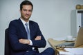 Hes the man to get the job done. Portrait of a confident young businessman sitting with his arms crossed at a desk in an Royalty Free Stock Photo