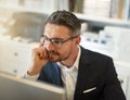 Hes the problem solver you want on your side. a businessman working at his computer in an office.