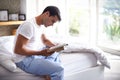 Hes quite the bookworm. a handsome young man reading a book on the edge of his bed. Royalty Free Stock Photo
