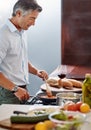 Hes quite the chef. a handsome mature man cooking dinner in his kitchen at home. Royalty Free Stock Photo