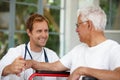 Hes a supportive healthcare professional. a handsome male doctor talking to his senior patient whos in a wheelchair. Royalty Free Stock Photo