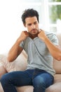 Hes too sexy for his shirt. a handsome young man taking off his shirt while sitting on the sofa at home. Royalty Free Stock Photo