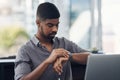 Hes a very efficient employee. a young businessman checking the time while working on a laptop in an office. Royalty Free Stock Photo