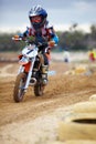 Hes way ehead of the pack. A young motocross rider coming round a bend on a track.