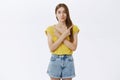 Hesitant attractive slender woman with cute braid in yellow t-shirt crossing hands against chest pointing left and right