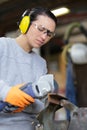 hesitant woman using noisy angle grinder Royalty Free Stock Photo