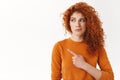 Hesitant worried cute modest redhead curly-haired female, looking pointing left dissatisfied and doubtful, have concern