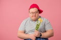 Hesitating plump man waiting for girlfriend with flowers on pink background