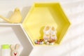 Hexagon shaped shelves with toys and child`s accessories on white wall. Interior design